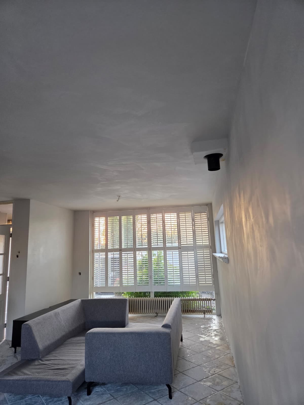 Gestukt plafond in een woonkamer met witte shutters